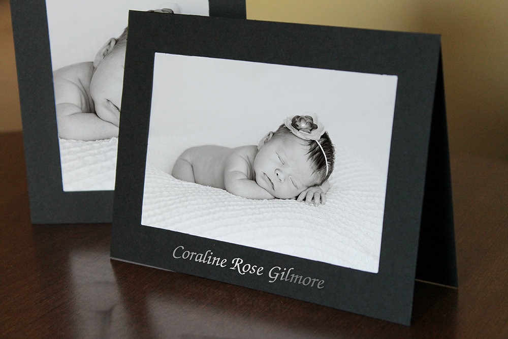 Black photo card with newborn's name stamped on the frame