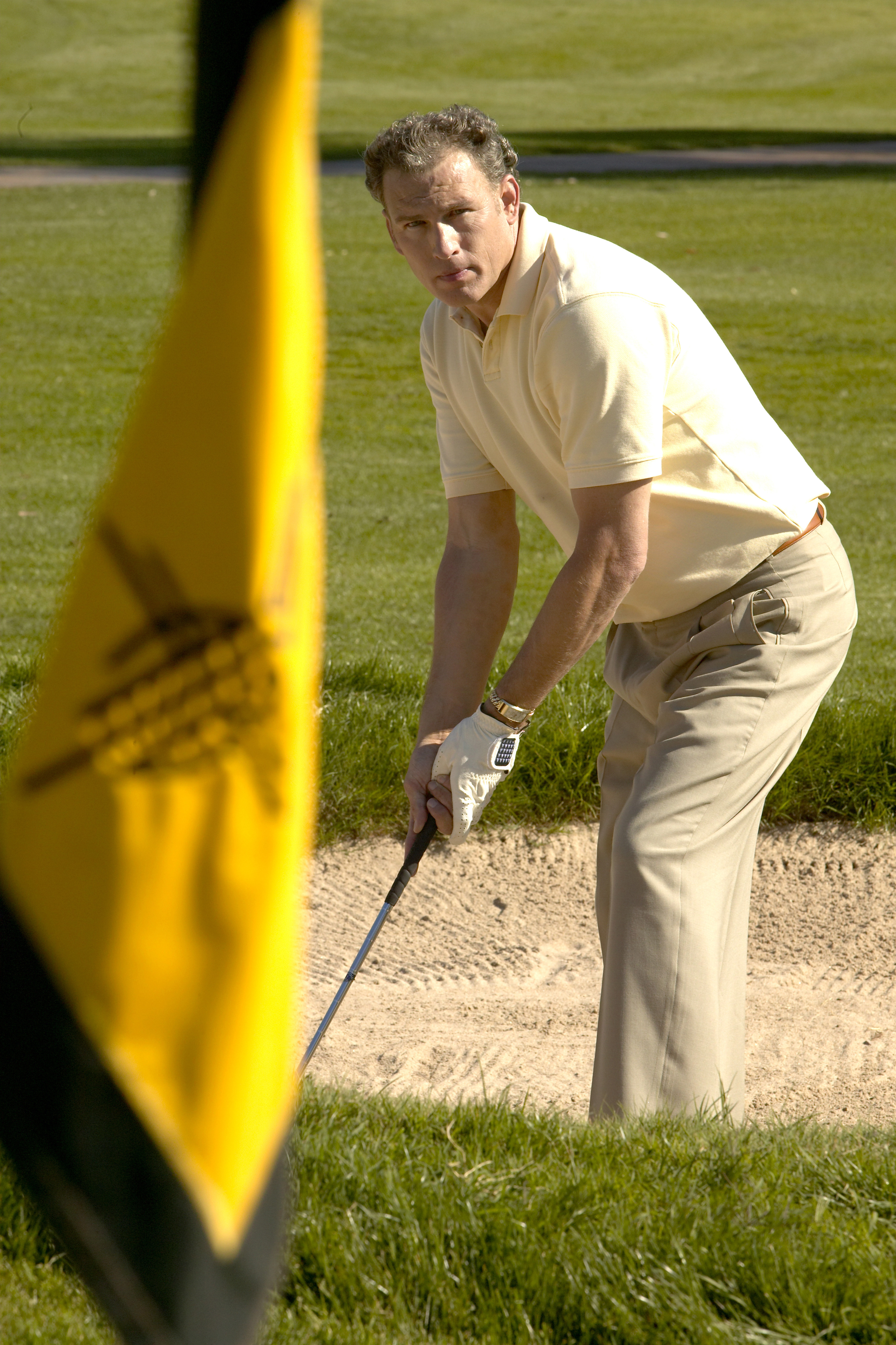 Man tries to chip a golf ball into the hole from a sand trap