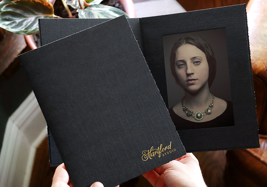 Vintage-styled black portrait folder with deckle edges and textured finish.