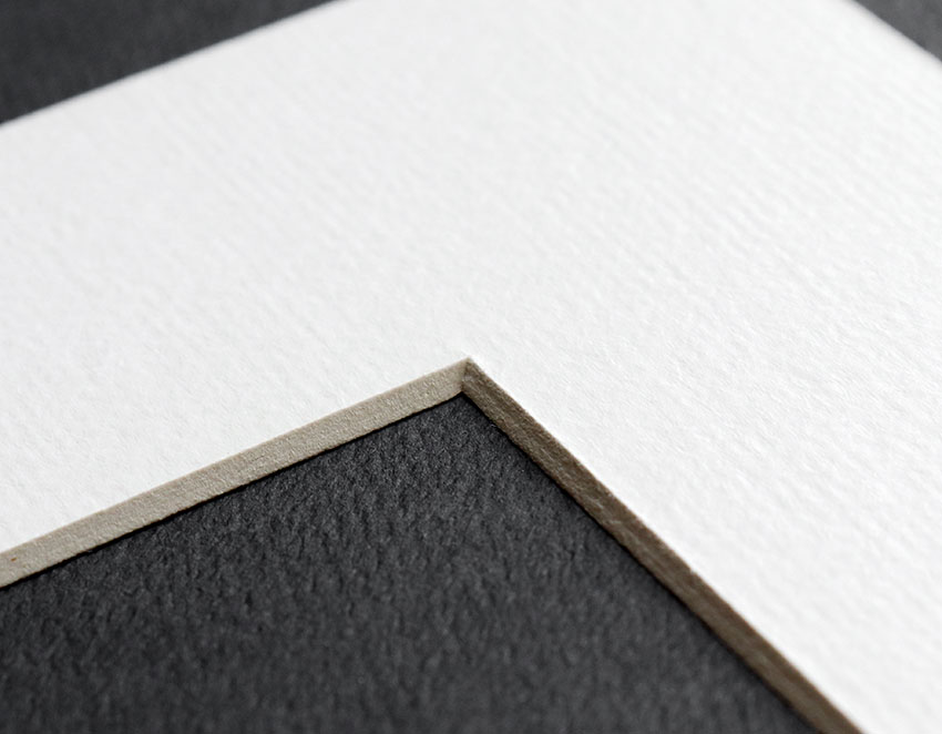 Edge detail of beveled edge cut on a white mat board frame