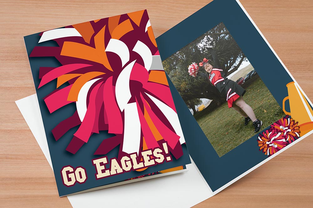 Photo folder with a colorful pom pom design says Go Eagles! Photo of enthusiastic cheerleader inside the folder.