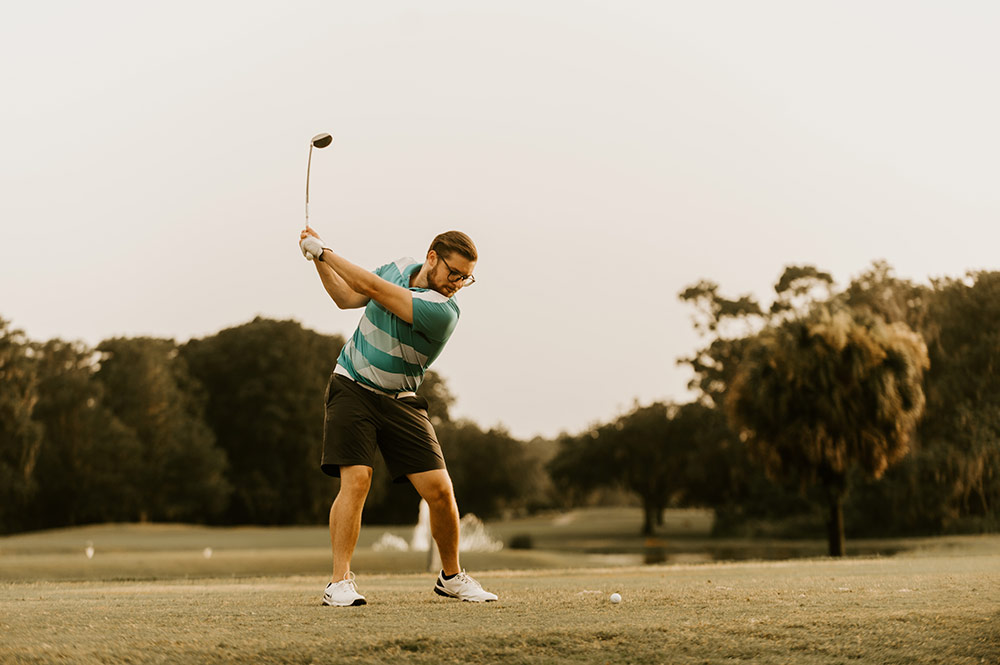 Action shot of a male golfer teeing off on a golf course