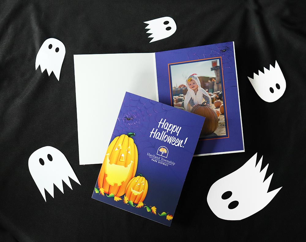 Jack-o-lantern photo folder with park district imprint frames a picture of a child in a chicken costume at a pumpkin patch.