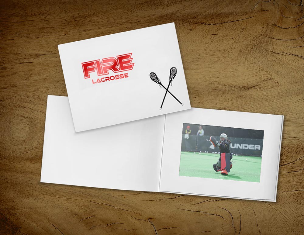 White photo folder with lacrosse stick design and team logo imprinted on the front cover, frames lacrosse athlete inside the folder.