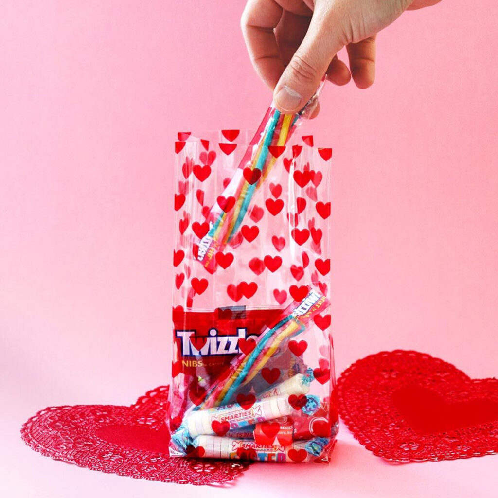 Someone is taking candy out of a clear goodie bag with a red heart pattern