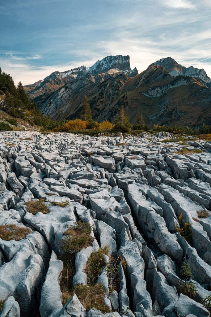 Some craggy, snow-dusted mountains are in the background. A fissured, rocky landscape in the foreground has lines that draw you eye to the mountains.