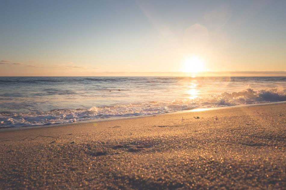 Gentle lapping waves from the ocean meet the beach at sunset. 