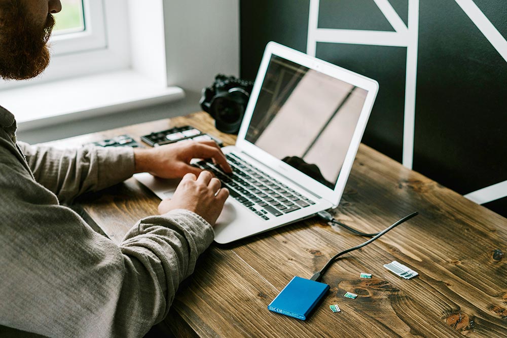 A photographer edits photos on a laptop at a desk.